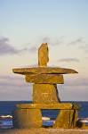 The sun begins to set on an inukshuk situated on the shores of Hudson Bay in the town of Churchill, Manitoba.  The inukshuk is a stone landmark traditionally used by northern aboriginal peoples to mark a route through the tundra of the arctic.